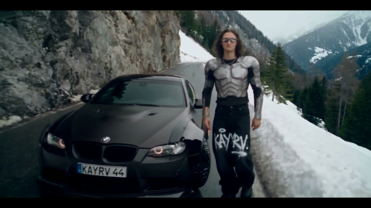 KAYRV standing beside a black car on a snowy mountain road
